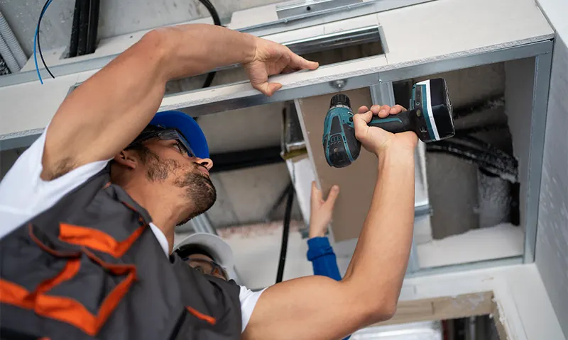 Electricista instalando el cableado en un techo técnico